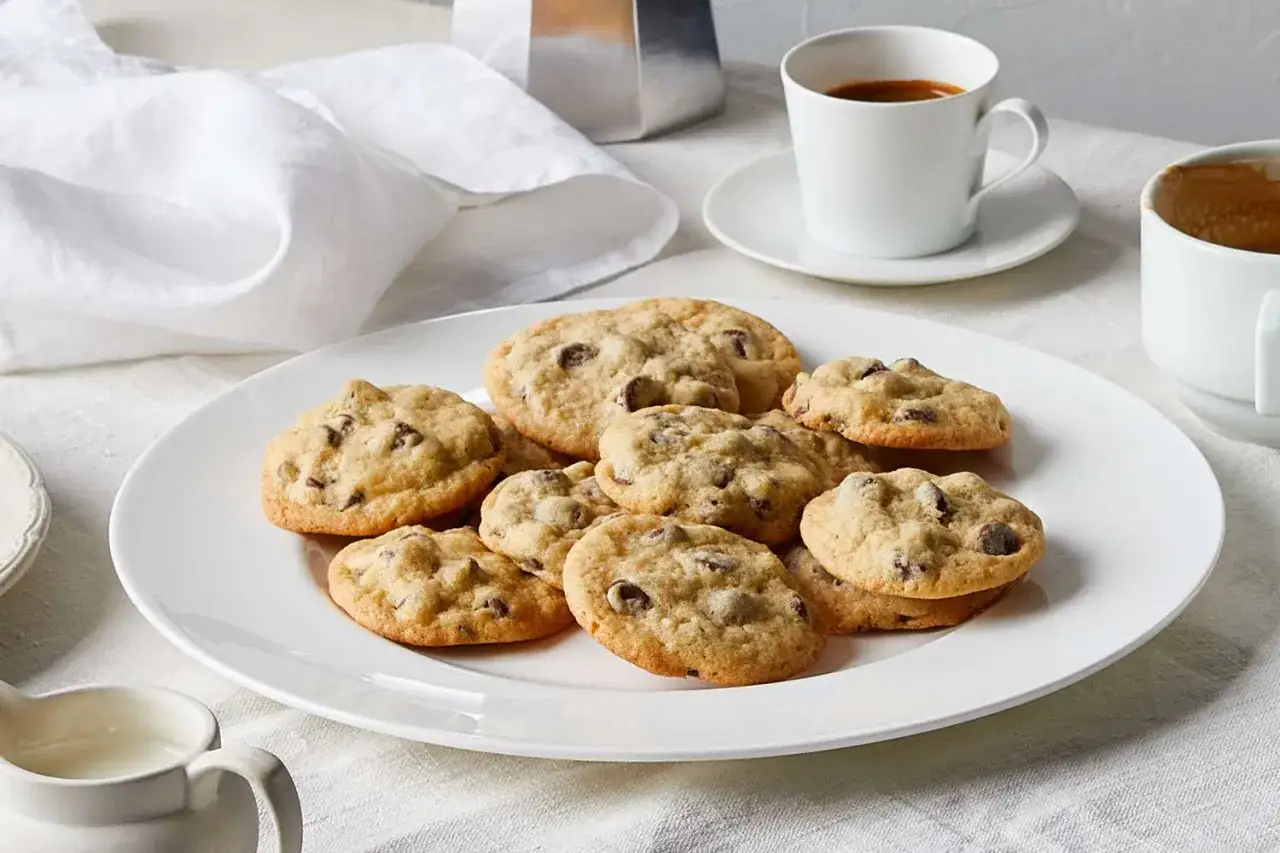 Ein Teller mit vielen saftigen american cookies, dazu eine Tasse Kaffee.
