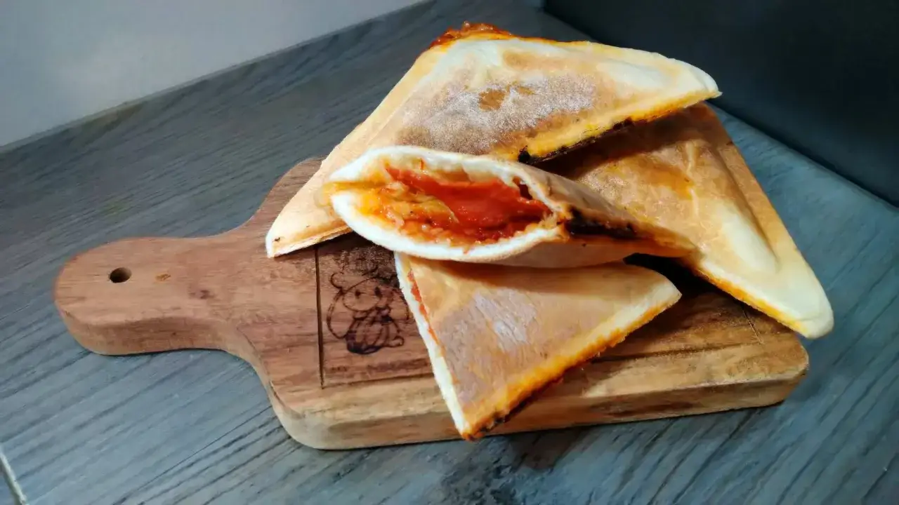 Dreieckige, goldbraune Sandwiches mit geschmolzenem K&auml;se und Tomatenf&uuml;llung, perfekt f&uuml;r schnelle Sandwichmaker Rezepte.