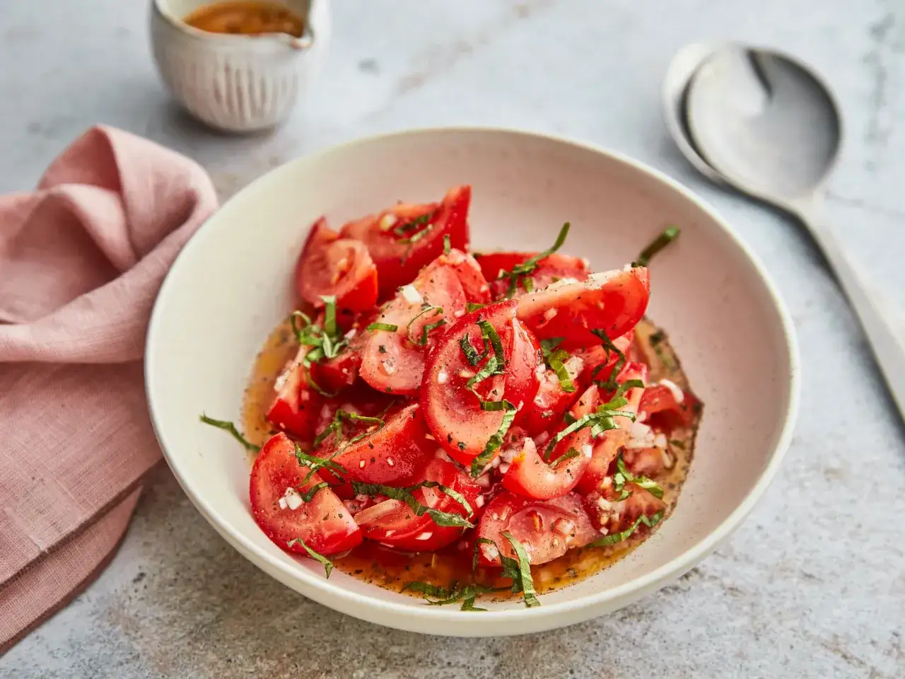 Frischer Tomatensalat mit Basilikum und Zwiebeln, ein einfaches Tomatensalat Rezept, serviert in einer Schüssel mit Dressing.