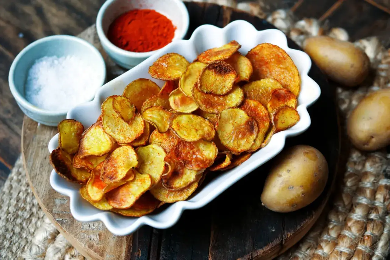 Selbstgemachte Kartoffelchips, goldbraun und knusprig, mit Salz und Paprikapulver. So einfach kannst du Chips selber machen!