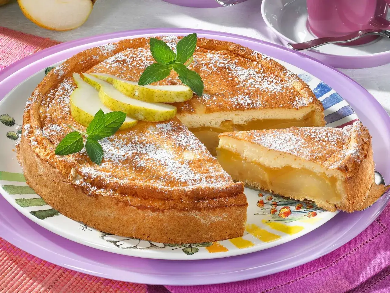 Ein saftiger birnenkuchen mit pudding, bestäubt mit Puderzucker und garniert mit frischen Birnenspalten und Minze.