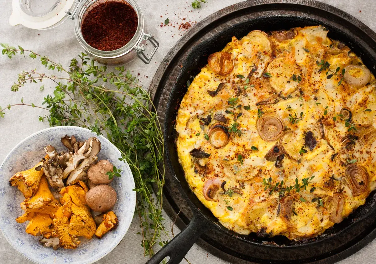 Herzhafte Kartoffel-Pilz-Frittata, inspiriert von leckeren Champignons Rezepten. Frische Kr&auml;uter und Gew&uuml;rze daneben.