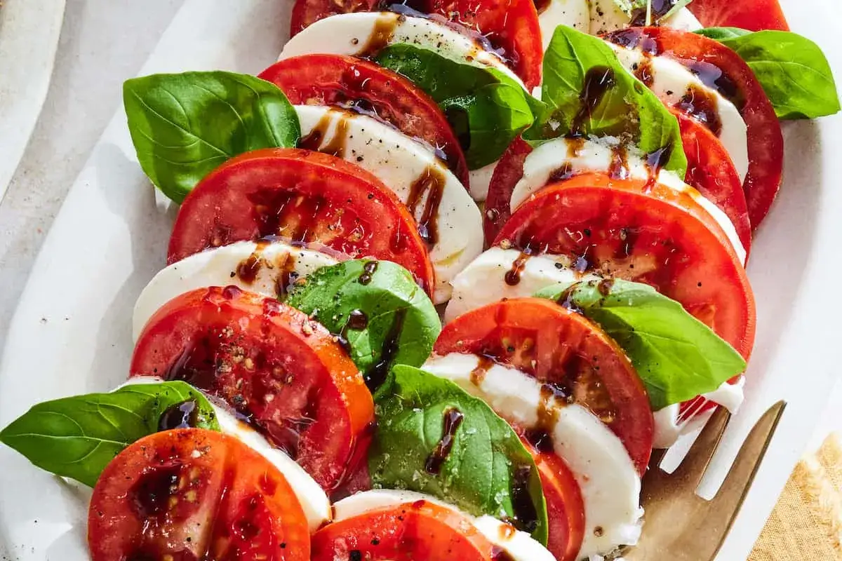 Frischer Tomate Mozzarella Salat mit Basilikum, beträufelt mit Balsamico-Glasur. Ein Klassiker, der immer schmeckt.
