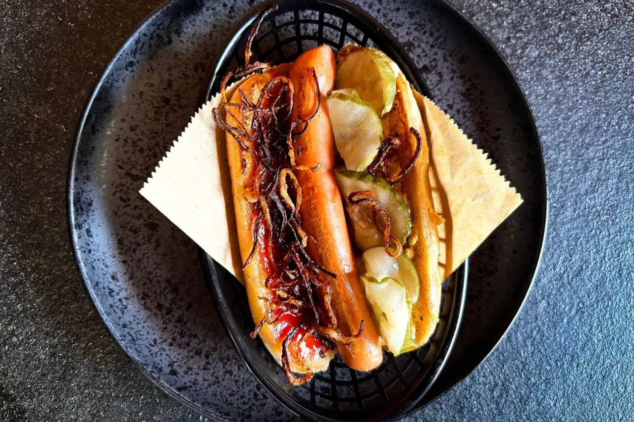 Ein Hotdog mit Gurkenscheiben und knusprigen Zwiebeln, ein einfaches, aber köstliches Hotdog-Rezept.