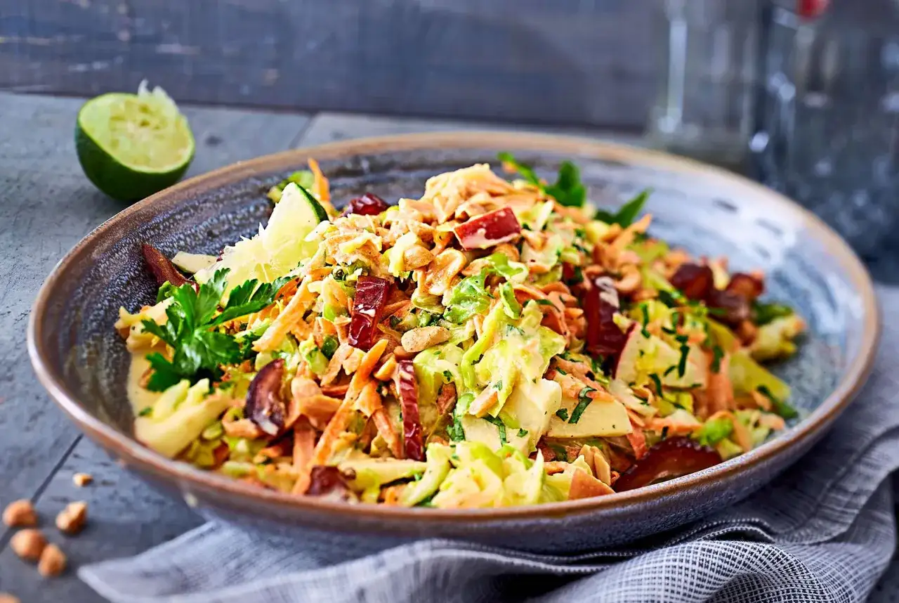 Frischer Spitzkohl Salat mit Karotten, Äpfeln und Nüssen, garniert mit Limette und Petersilie. Ein Genuss!