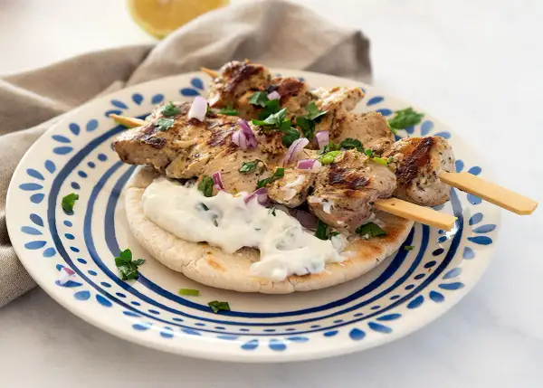 Saftige Hähnchen-Souvlaki-Spieße auf Pitabrot mit Tzatziki und roten Zwiebeln. Ein köstliches Souvlaki Rezept für den Sommer.