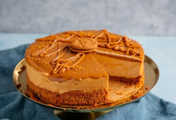Ein köstlicher Lotus Kuchen mit Mascarpone, dekoriert mit Karamell und Kekskrümeln. Ein Stück fehlt bereits.