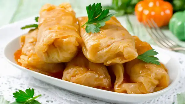 Kohlrouladen mit Hackfleisch in Sauce auf einem Teller, garniert mit Petersilie.