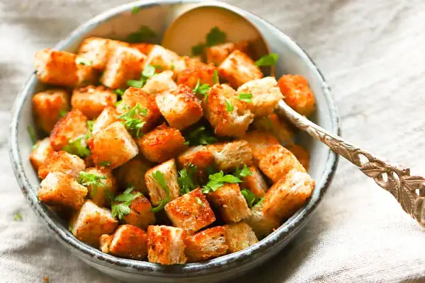 Goldbraune, knusprige Croutons mit Petersilie garniert, perfekt zum Salat. So einfach kannst du Croutons selber machen!