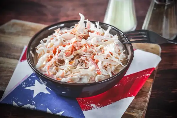 Schüssel mit cremigem Krautsalat, perfekt für Ihr coleslaw rezept. Ein Gabel liegt bereit.