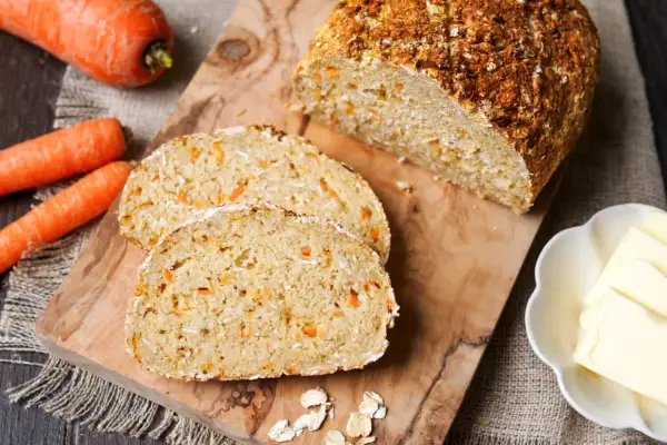 Frisch gebackenes Karottenbrot mit Haferflocken, perfekt für das brot backen im airfryer. Dazu Butter und ganze Karotten.