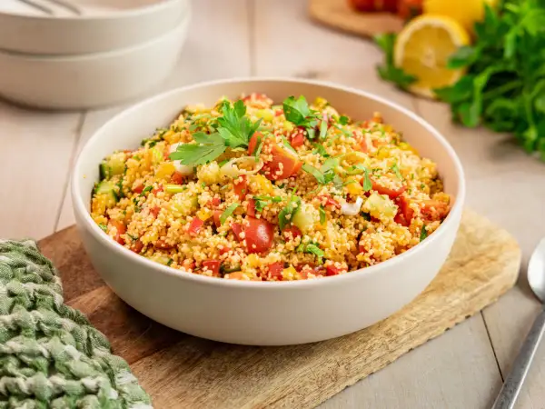 Ein klassisches Couscous-Salat Rezept, frisch zubereitet mit Tomaten, Gurken, Paprika und Kräutern, garniert mit Petersilie.