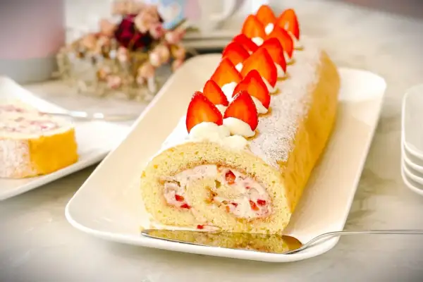 Ein köstliches Biskuitrolle Rezept mit frischen Erdbeeren und Sahne, bestäubt mit Puderzucker. Perfekt für jeden Anlass!