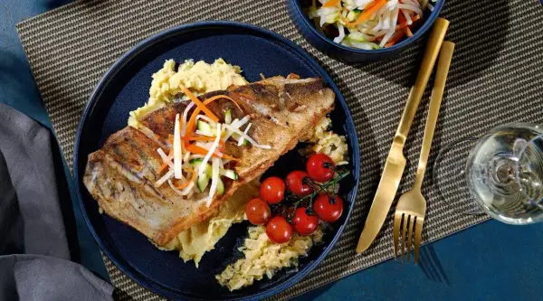 Gebratener Fisch auf Kartoffelpüree mit Kirschtomaten und knackigem Gemüse. Eine köstliche Beilage, die gut zu Kabeljau passt.