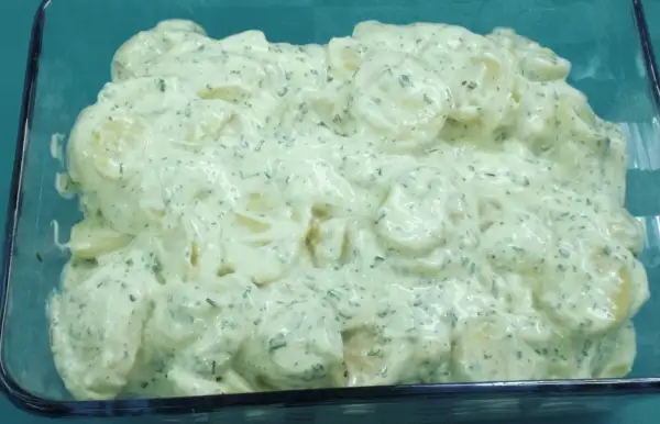 Cremiger Kartoffelsalat mit Kräutern und einem Hauch Balsamico, serviert in einer Glasform.